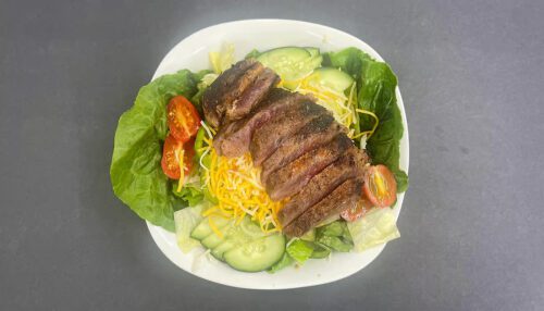 Salad with steak, lettuce, tomato, cheese, cucumber